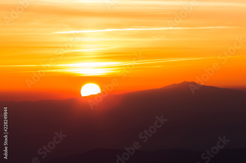 Beautiful sunset with sun coming down behind various layers of mountains
