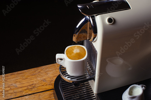 Coffee machine with cup of coffee  Espresso machine making coffee with capsules background on wood