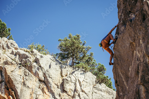 Young man climbs the yellow rock, hard route 7c, lead.