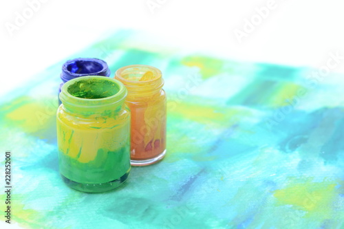 Bottles of colorful paint on watercolor paper,art equipments concept.