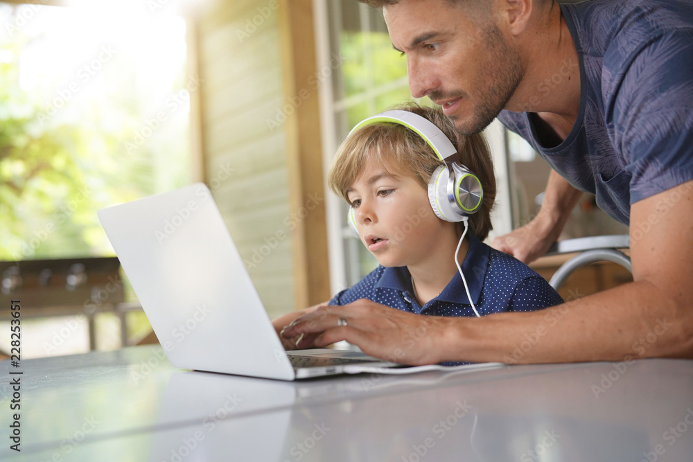 Little boy using laptop with help of daddy Little boy using laptop with help of daddy