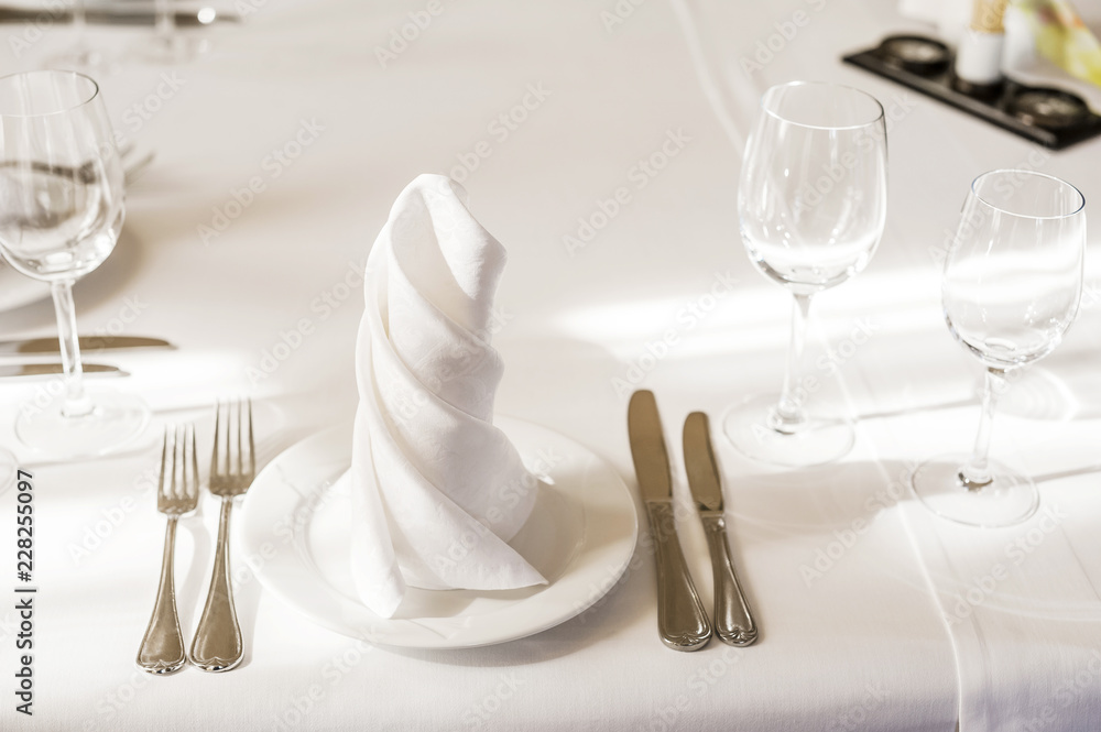 Spun white napkins on a white plate on a served table. Plate in a cafe or restaurant with a napkin and appliances Spun white napkins on a white plate on a served table. Plate in a cafe or restaurant with a napkin and appliances