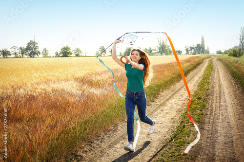 Beautiful young woman flying kite in a field