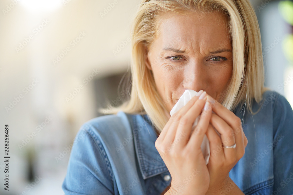 Middle-aged woman with allergy blowing her nose Middle-aged woman with allergy blowing her nose