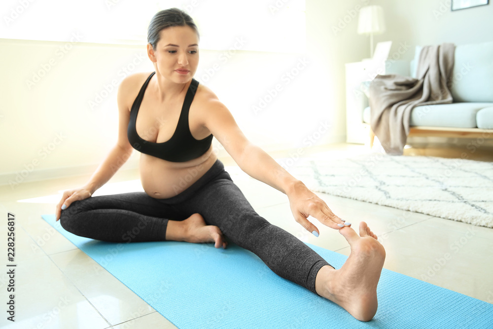 Young pregnant woman practicing yoga at home Young pregnant woman practicing yoga at home