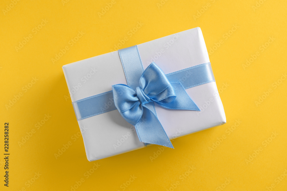 Gift box with blue ribbon on color background Gift box with blue ribbon on color background