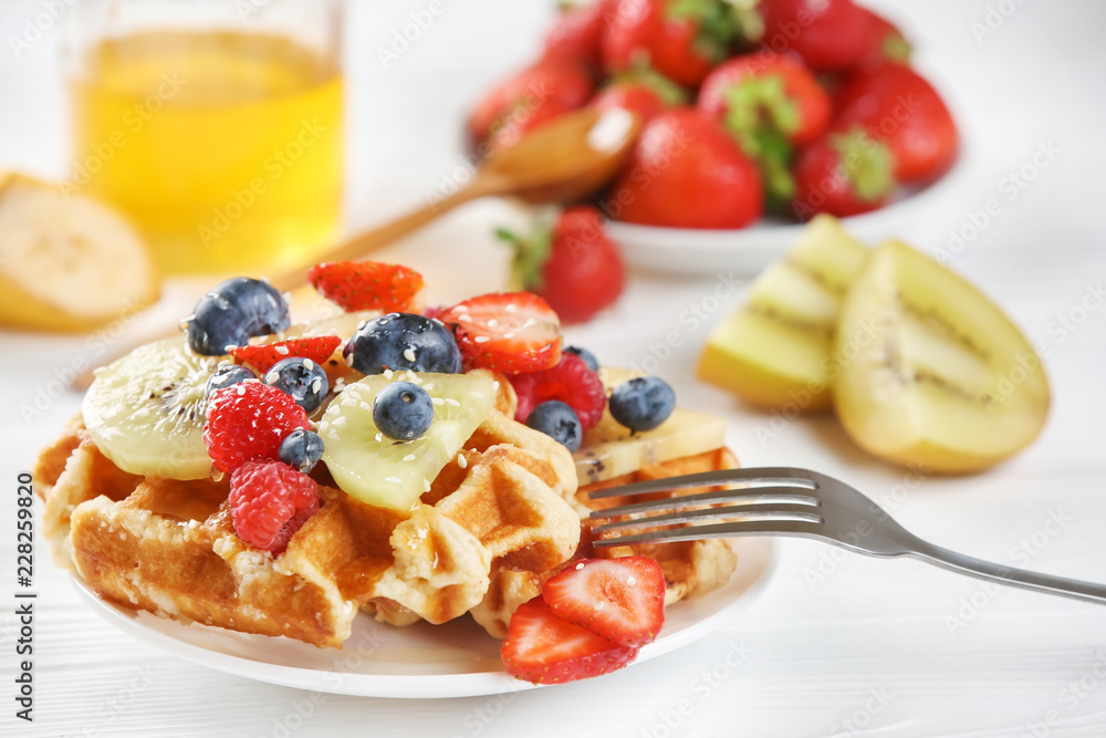 Delicious waffles with berries and kiwi slices on plate