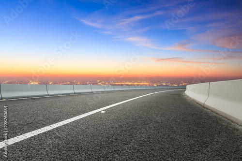 Modern city skyline and buildings with empty asphalt road at sunset © ABCDstock