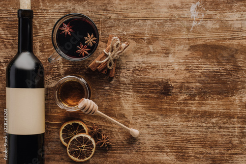 elevated view of mulled wine, honey and wine bottle on wooden table