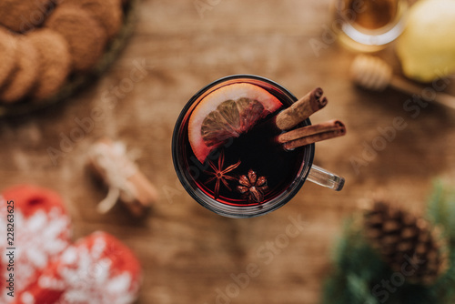 top view of mulled wine with cinnamon sticks and lemon in glass on wooden tabletop, christmas concept