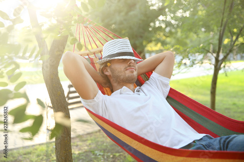 Handsome young man resting in hammock outdoors photo