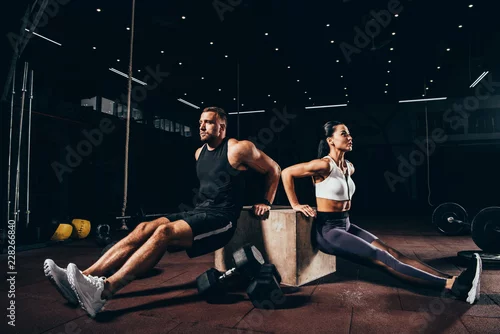 Panel kuchenny z motywem Athletic sportsman and sportswoman exercising on cube together in dark gym