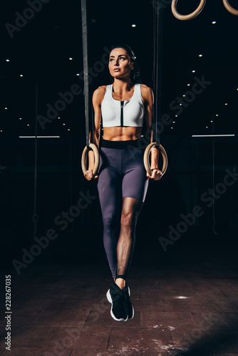 attractive athletic sportswoman exercising with gymnastic rings