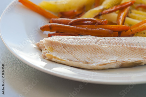 Tasty baked fish with fried fries and carrot slices on plate