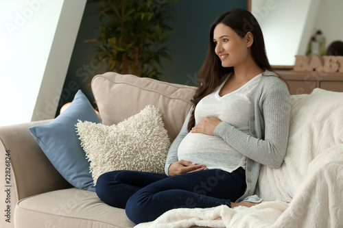 Beautiful pregnant woman resting on sofa at home