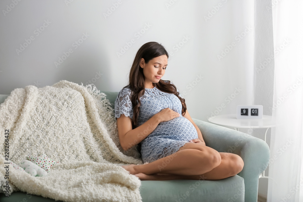 Beautiful pregnant woman sitting on sofa at home Beautiful pregnant woman sitting on sofa at home