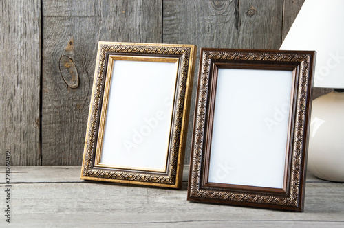 Two empty picture frames on wooden background.