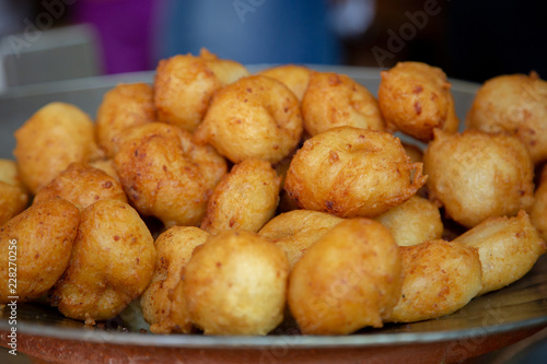 Bunyols, Buñuelos, round doughnuts balls made from a potato or cassava dough and cooked in hot oil. Traditional snack popular in Spain and Latin America. Side view. Macro, close up.