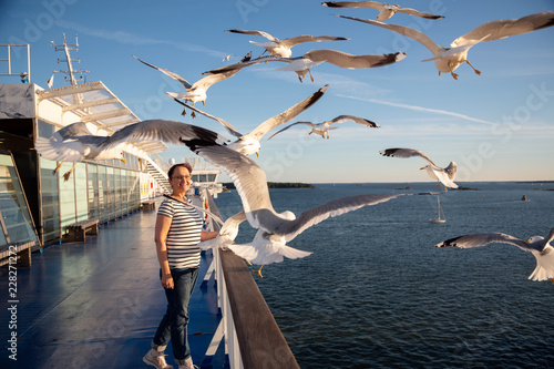 Older woman watching seagulls flying. Photo of a middle aged lady on the cruise ship deck in a Baltic Sea cruise.