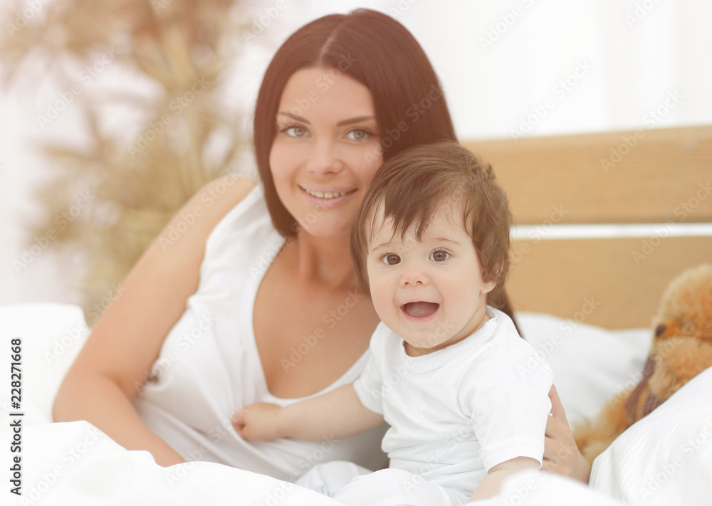 Portrait of a beautiful mother with her baby in the bedroom Portrait of a beautiful mother with her baby in the bedroom