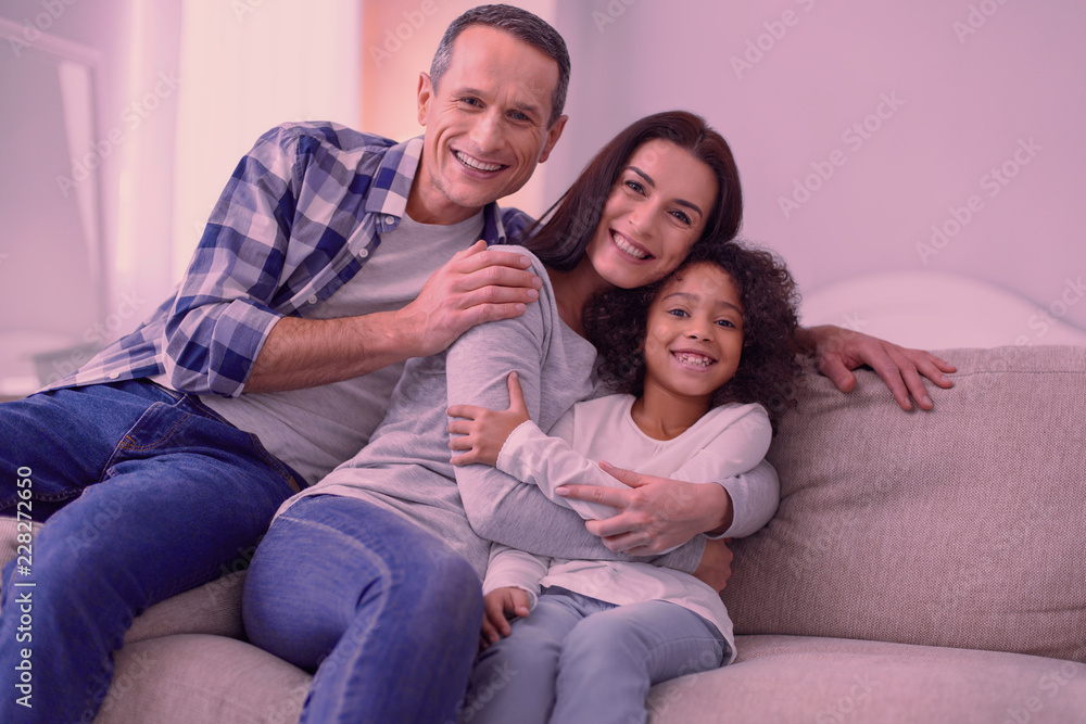 Family day. Joyful happy family sitting together on the sofa while relaxing at home Family day. Joyful happy family sitting together on the sofa while relaxing at home