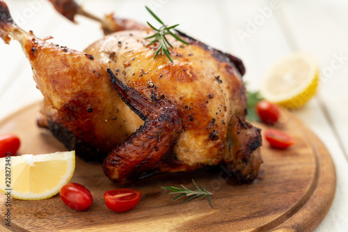 Roasted chicken with tomatoes on wooden cutting board