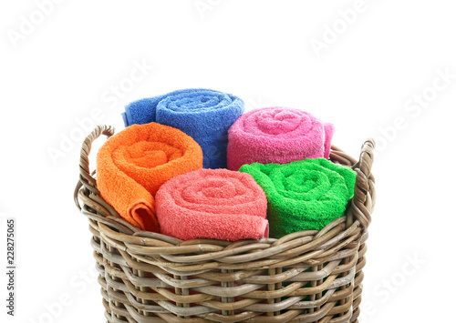 Wicker basket with rolled bright towels on white background
