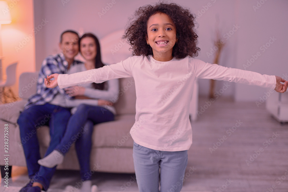 Fototapeta premium Happy childhood. Delighted nice girl standing in the room while feeling very happy