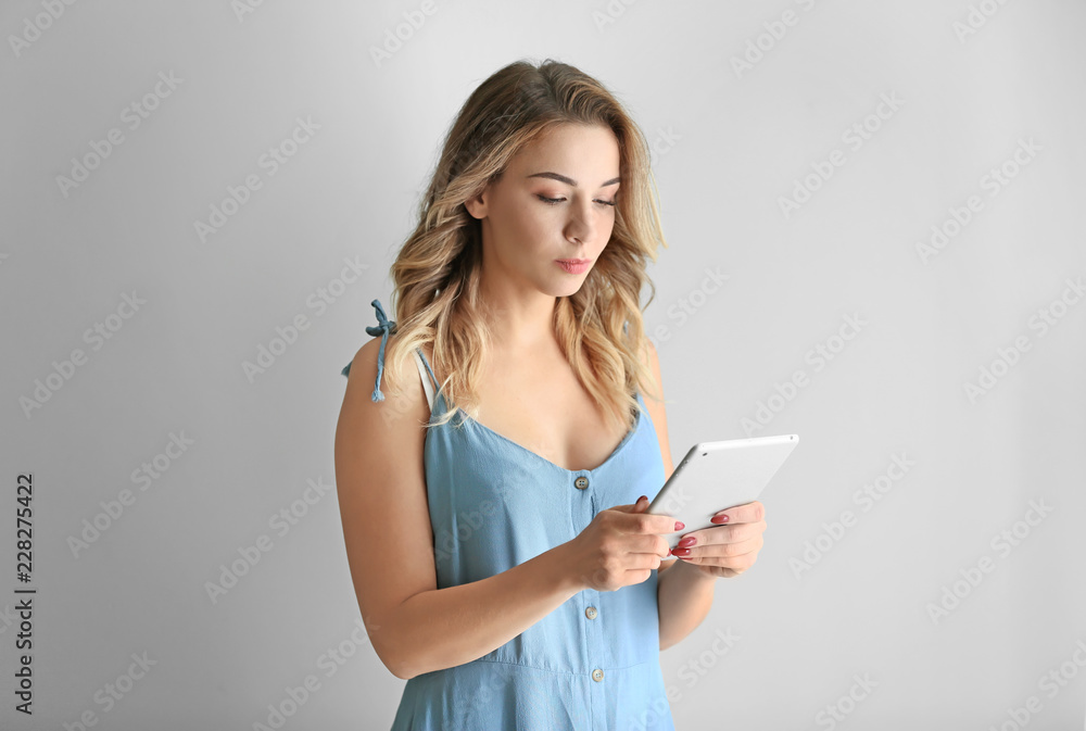 Portrait of beautiful young woman with tablet computer on grey background Portrait of beautiful young woman with tablet computer on grey background