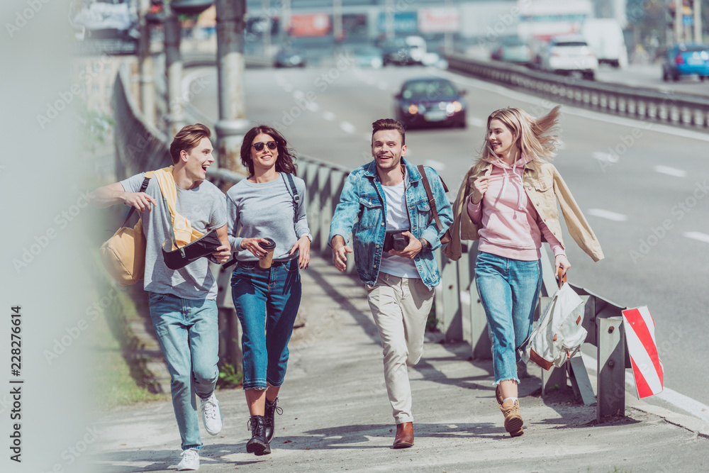 Fototapeta premium happy friends with map and backpacks traveling together in new city