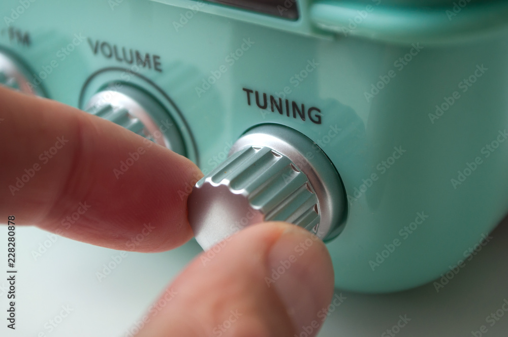 Φωτογραφία closeup of hand of man turning vintage fifties style radio buttons on white back