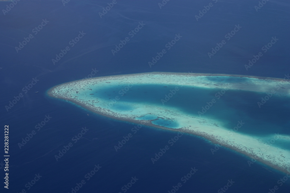 Blue and turqouise coral reef and atol, in the Maldives, aerial view, panorama from the air. 