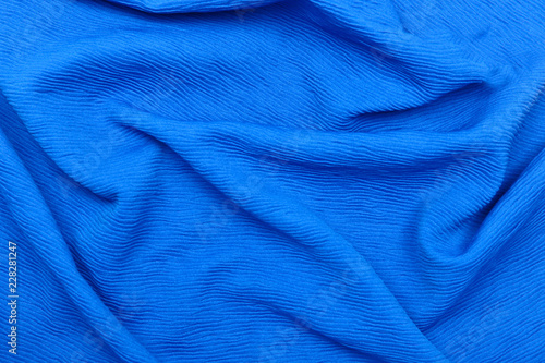 Background and texture. The concept of hobby and production. Image of the texture of fabric for sewing clothes. Blue knitwear, wool. Abstraction. Cropped shot, isolated, close-up, blurred, horizontal