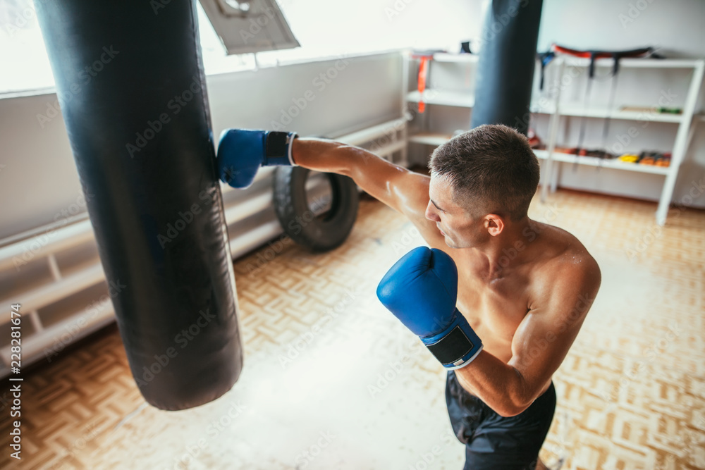 Male boxer hitting punching bag at a boxing studio Male boxer hitting punching bag at a boxing studio