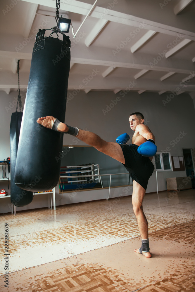Male boxer hitting punching bag at gym