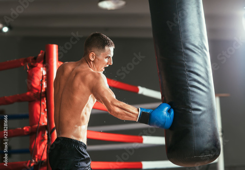 Male boxer hitting punching bag at a boxing studio © GVS