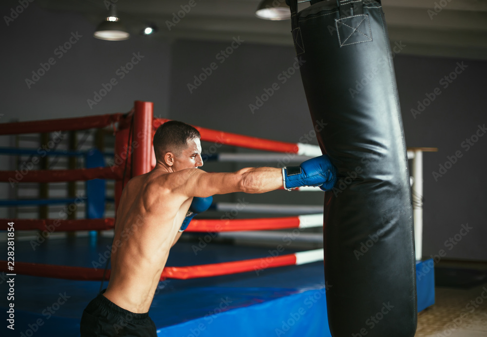 Male boxer hitting punching bag at a boxing studio