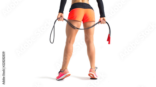 Close up of slender female legs. Girl is holding a skipping rope. Copy space.