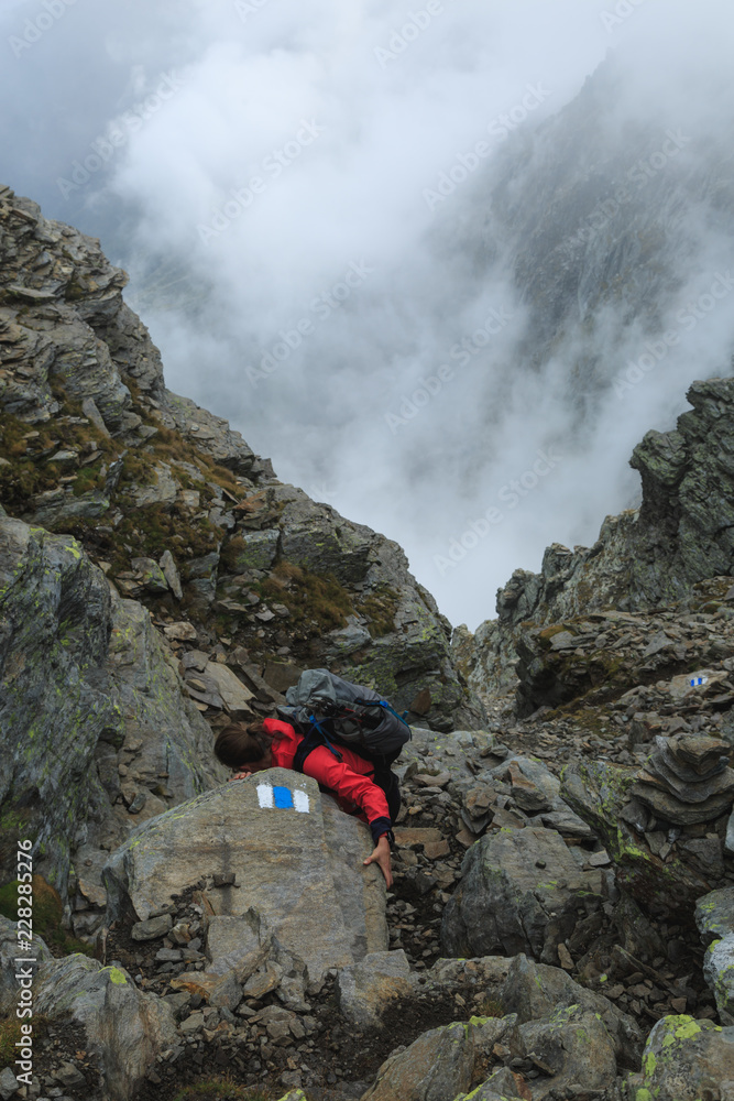 Female hiker climbing down on the steep route of the Via Alta Verzasca in Ticino, Switzerland.