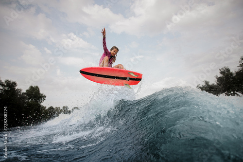 Photography Active woman jumping up the blue slashing wave against the grey sky