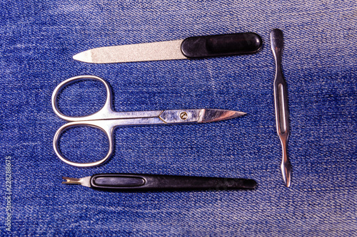 Different manicure tools on a blue jeans background. Top view