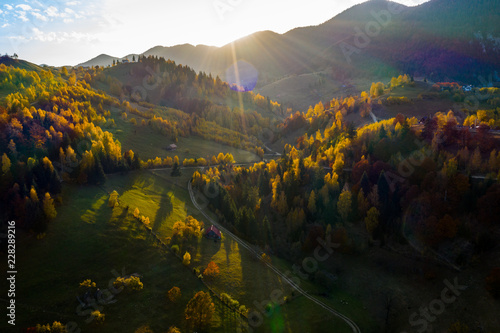 Beautiful sunset over the mountain forest in autumn season, October. Colors of the forest in the sunset light from above. Aerial view over the colorful forest of autumn season in the mountains. Magura