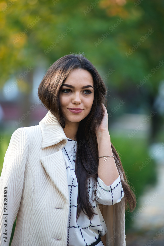 Young beautiful business lady is standing in the park in autumn. Young beautiful business lady is standing in the park in autumn.