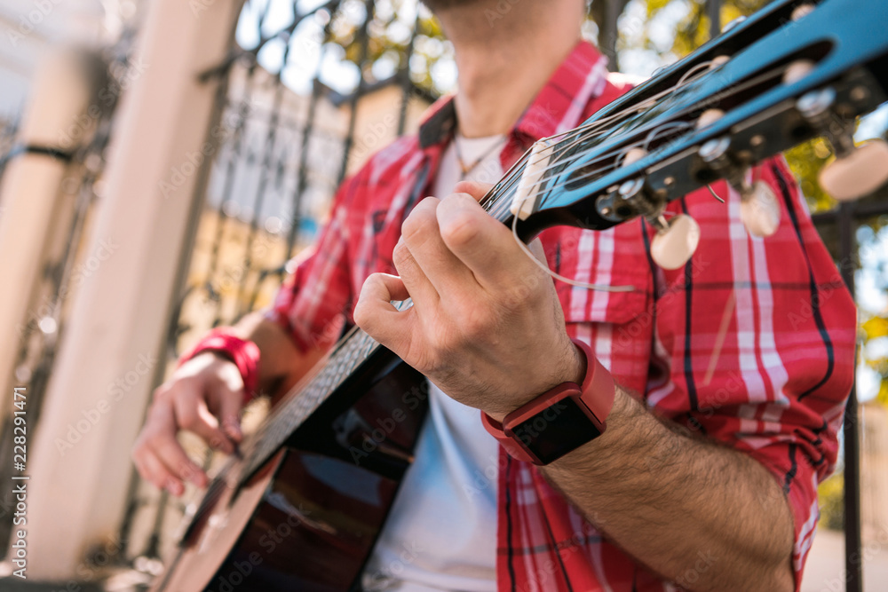 Best music instrument. Close up of appealing male hands playing on instrument and holding chord