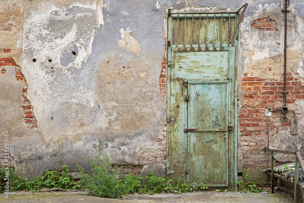 Fototapeta premium grunge metal door, cracked red brick wall background