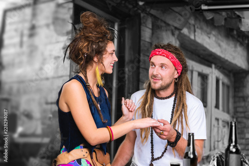 Hand touch. Handsome man with dreadlocks wearing red head band taking hand of his lovely appealing girlfriend