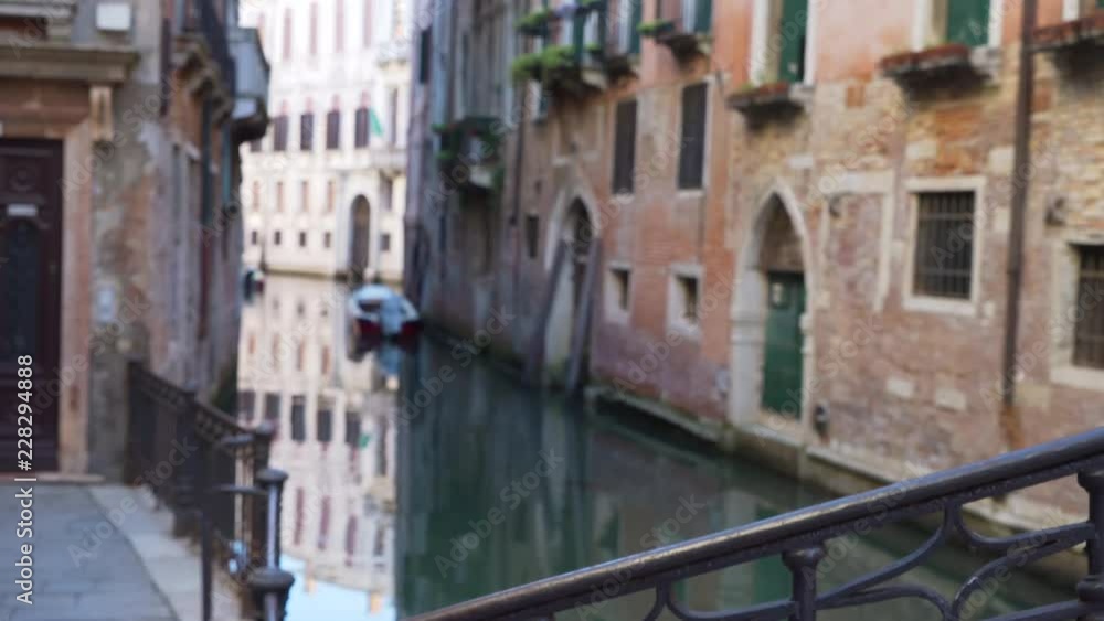 Typical Venetian homes with arched doorways and windowsills with plants on a narrow canal View from behind iron rail of old Italian structure with weathered stonework 4k Typical Venetian homes with arched doorways and windowsills with plants on a narrow canal View from behind iron rail of old Italian structure with weathered stonework 4k