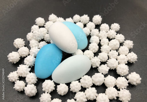 Tableau sur toile White and turquoise sugared almond or comfits on blue background.