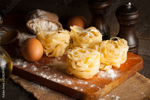 Closeup of raw homemade pasta with ingredients on wooden  rustic background. Pasta  salt  eggs  yolk  pepper. Home made food concept.