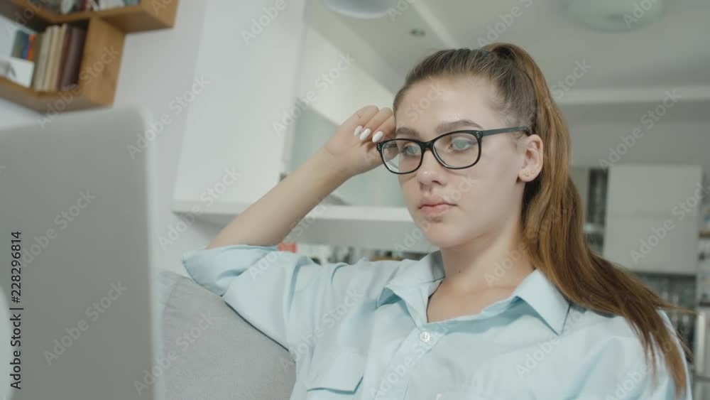 Embarrassed teenage girl student is using a laptop at home, typing on notebook, preparing for exams or homework Embarrassed teenage girl student is using a laptop at home, typing on notebook, preparing for exams or homework